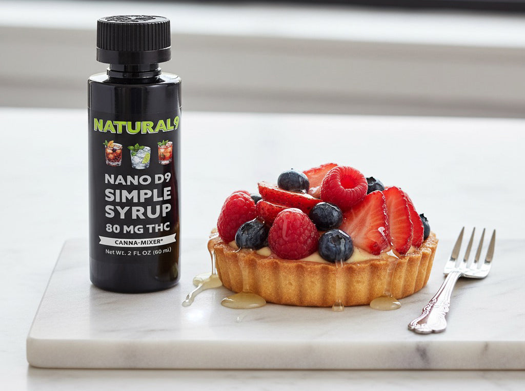 2oz black plastic bottle of Natural9 Nano THC Simple Syrup next to a fruit tart on a white Danby marble surface.